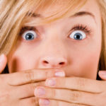 Closeup of young women covering her mouth with both hands